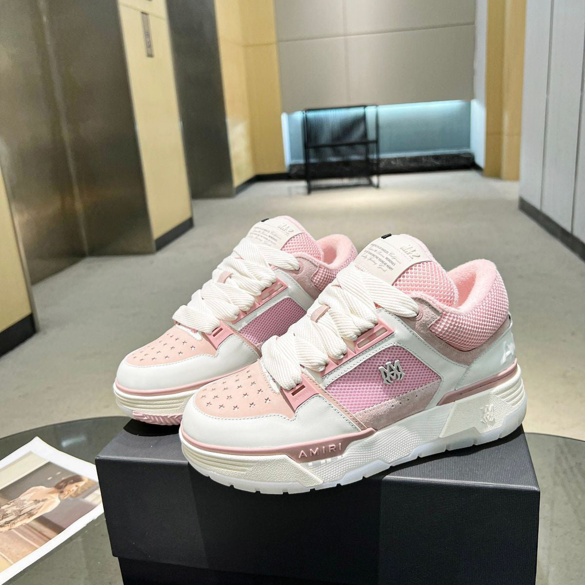 Pink and white sneakers on a black box in an indoor setting